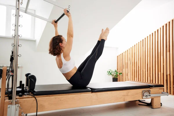 Woman Doing Pilates Reformer Bed Bright Studio Slender Flexible Brunette — Stock Photo, Image