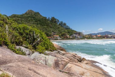 Sahilde kayalar, orman, evler ve dağ Canto Grande plajı, Bombinhas, Santa Catarina, Brezilya