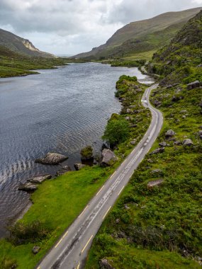 Dunloe Gap 'teki yol ve göl manzaralı kayalar ve bitki örtüsü Killarney, Kerry, İrlanda