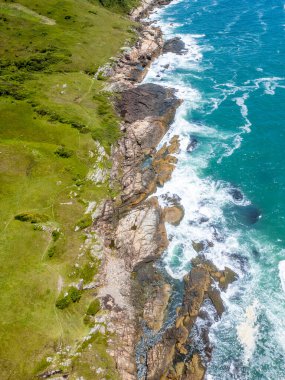 Casqueiro patikasında kayalar ve bitki örtüsü olan sahil, Garopaba, Santa Catarina, Brezilya
