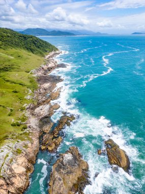 Beach with rocks and vegetation at Casqueiro trail, Garopaba, Santa Catarina, Brazil clipart