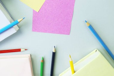 Books, sketchbook and colorful pencils on the table, top view, save space, back to school concept, education, school supplies