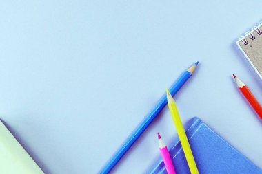 Books, sketchbook and colorful pencils on the table, top view, save space, back to school concept, education, school supplies