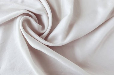 Beige color natural silk draped with folds, top view, fabric texture, pastel shades background