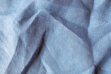 Keten kumaş, pastel gri-mavi renk tonu, buruşuk doğal kumaş dokusu, üst görünüm.