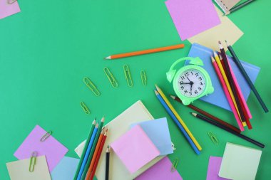 Okul malzemeleri ve yeşil arka planda bir çalar saat. Okul konseptine dönelim.