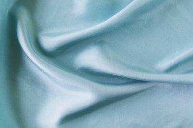 Açık mavi renk kıvrımlı doğal ipek, üst görünüm, saten kumaş dokusu, pastel tonu.