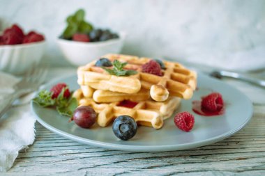 Ahududulu Belçika waffleları, ahşap zemin üzerinde yaban mersini ve nane şekeri, ev yapımı pastalar, kahvaltı