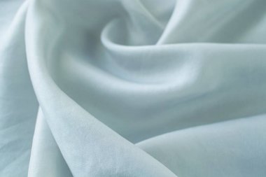 Açık gri renk, kıvrımlara sarılı doğal ipek, üst görünüm, saten kumaş dokusu, pastel tonu.