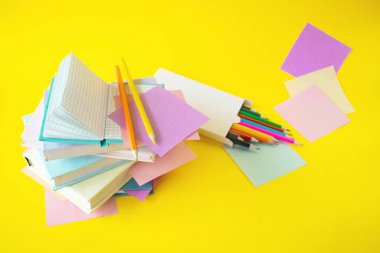 Okula, kitaplara, renkli yapışkan notlara ve sarı arka planda fotokopi alanlı kalemlere.