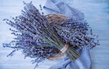 Tahta bir masada sepetin içinde lavanta çiçekleri.