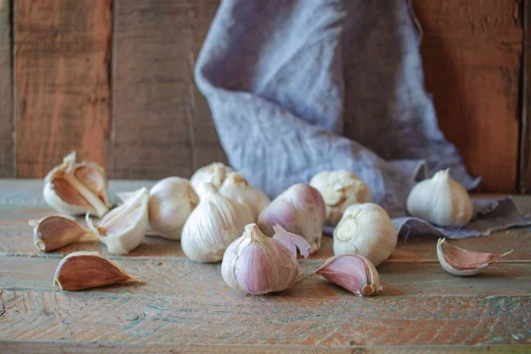大蒜球茎和大蒜丁香在乡村木背景上 亚麻布织物 免版税图库照片