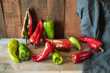 Ahşap zemin üzerinde kırmızı ve yeşil biberler mevsimlik organik sebzeler. 