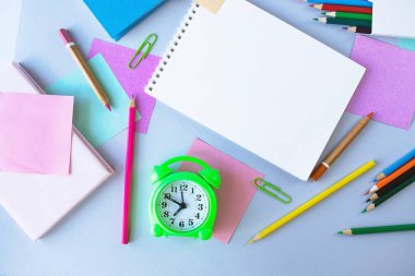 Okula, çalar saate, renkli yapışkan notlara ve renkli kalemlere, gri arkaplana fotokopi alanı, üst görünüm, düz çizim malzemelerine