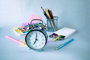 Okula dönüyorum, suluboya resimler, fırçalar, renkli kalemler, paletler, gri arka planda okul malzemeleri.