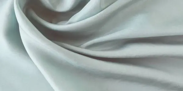 Açık gri renk, kıvrımlara sarılı doğal ipek, üst görünüm, saten kumaş dokusu, pastel tonu.