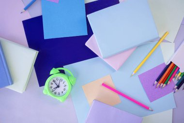 Okula geri dön, kırtasiye, çalar saat, kitap yığını, kağıt ve renkli kalemler öğrenci masasına, üst görünüm