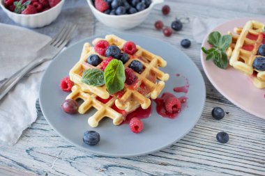 Ahududulu Belçika waffleları, ahşap zemin üzerinde yaban mersini ve nane şekeri, ev yapımı pastalar, kahvaltı