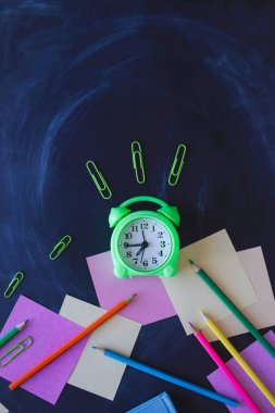 Okul konseptine geri dönelim. Okul gereçleri ve alarm saati yazı tahtası arka planında fotokopi alanı, üst görünüm.