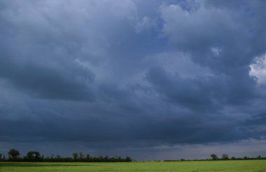 Tarlanın üzerinde fırtına bulutları var. Kasvetli, karanlık ve dramatik gökyüzü yağmurdan önce, kümülonimbus bulutları, gün. Doğa arkaplanı.  