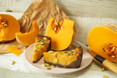 Kabak çekirdekli balkabağı turtası ve ahşap zemin üzerinde balkabağı dilimleri..