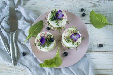 Salatalık dilimleri, mikroyeşillikler ve taze mor çiçeklerle süslenmiş beyaz peynir ile vejetaryen aperatifi..
