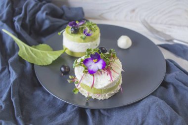 Salatalık dilimleri, mikroyeşillikler ve taze mor çiçeklerle süslenmiş beyaz peynir ile vejetaryen aperatifi..