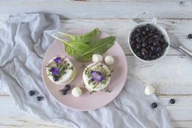 Salatalık dilimleri, mikroyeşillikler ve taze mor çiçeklerle süslenmiş beyaz peynir ile vejetaryen aperatifi..
