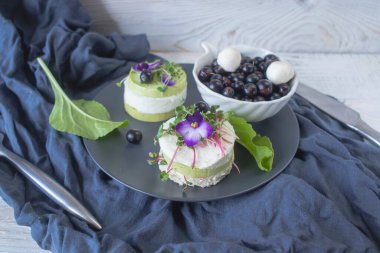 Salatalık dilimleri, mikroyeşillikler ve taze mor çiçeklerle süslenmiş beyaz peynir ile vejetaryen aperatifi..