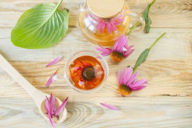 Ahşap arka planda cam çaydanlıkta Ekinezya çiçeği çayı. Ekinezya çiçeklerinden şifalı bitki çayı..