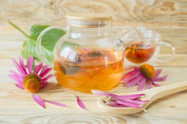 Ahşap arka planda cam çaydanlıkta Ekinezya çiçeği çayı. Ekinezya çiçeklerinden şifalı bitki çayı..