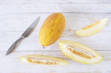 Beyaz ahşap arka planda olgun kavun dilimleri, yakın plan. Sağlıklı beslenme, vejetaryen yemekleri. Vitamin tatlısı.