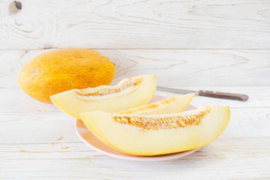 Beyaz ahşap arka planda olgun kavun dilimleri, yakın plan. Sağlıklı beslenme, vejetaryen yemekleri. Vitamin tatlısı.