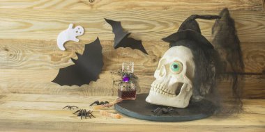 Cadılar Bayramı 'nda kafatası kuklası, örümcekler ve tahta arka planda cadı aksesuarları ile sakin bir hayat. Cadılar Bayramı iç dekorasyonu.