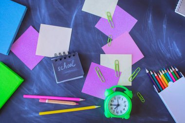 Okul konseptine geri dönelim. Tahta üzerine okul malzemeleri ve alarm saati. Okul malzemeleriyle dolu bir hayat. Üst manzara, düz uzanma. 