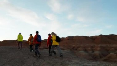 Seyahat grubu gün batımında dağın zirvesinde durup kollarını kaldırsın. Başarı sevinci, başarı, zafer ve motivasyon yüksek vahşi doğa manzarası
