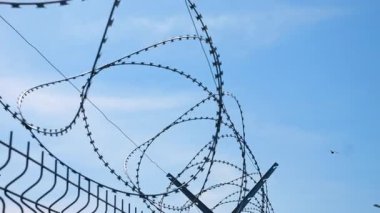 Korunma, koruma ve savunma için keskin dikenli telleri olan metal çitler, yasak bölgenin ayrılması ve kontrolü, özel endüstriyel bölge güvenliği kavramı.