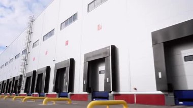 An exterior view of a massive modern distribution center for storing and delivering various goods to customers. Numerous gates are used for loading goods. Concept of production and supply