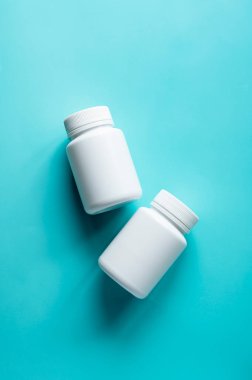 Mavi arka planda beyaz ilaç şişeleri. Sağlıklı gıda takviyeleri, vitaminler ve ilaçlar.