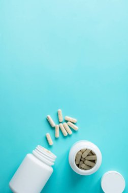 Mavi arka planda beyaz ilaç şişeleri. Sağlıklı beslenme malzemeleri, vitaminler ve ilaçlar. Boşluğu kopyala
