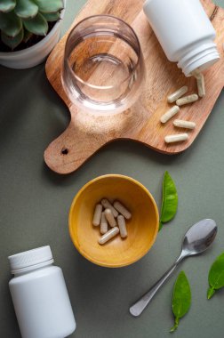 Yeşil arka planda beyaz hap şişeleri. Sağlıklı gıda takviyeleri, vitaminler ve ilaçlar.