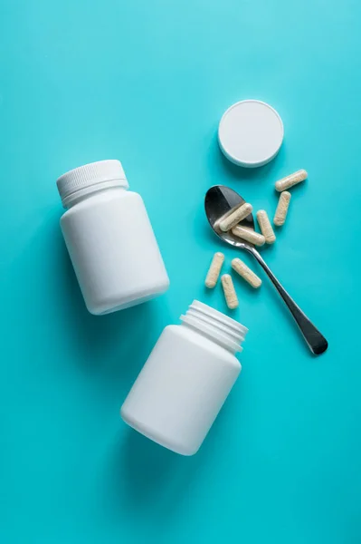 stock image White pill bottles on blue background. Health care food supplements, vitamins and medicaments.