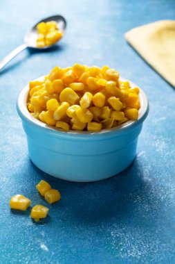 Mavi arka planda bir kase tatlı mısır.