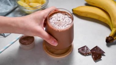 Muz, protein tozu ve kakaolu protein çikolatası. Sağlıklı bir fitness içeceği. Yüksek kaliteli FullHD görüntüler