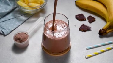 Muz, protein tozu ve kakaolu protein çikolatası. Sağlıklı bir fitness içeceği. Yüksek kaliteli FullHD görüntüler