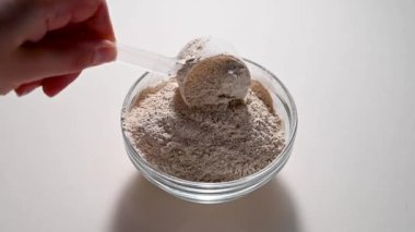 Bir kepçeyle bir kaba protein tozu ekliyorum. Gıda takviyesi spor beslenmesi