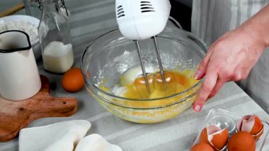 Mixing eggs with sugar. Female hands using hand mixer for cooking sweet dessert. . High quality FullHD footage