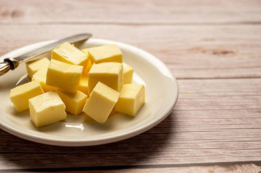 Butter cubes sliced, dairy product, cooking ingredient. Wooden background, top view