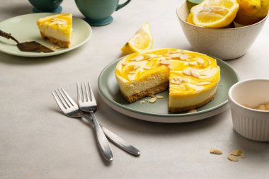 Lemon cheesecake tart or pie, with fresh lemons. Grey background.