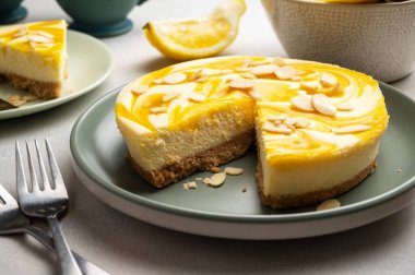 Lemon cheesecake tart or pie, with fresh lemons. Grey background.